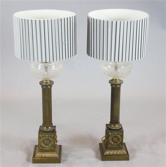 A pair of brass column oil lamps, height 23in., with shades 31in.